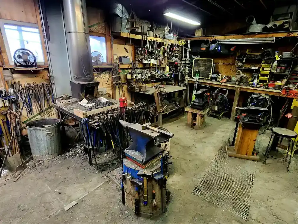 Blacksmithing shop showing anvils, forge and tools.